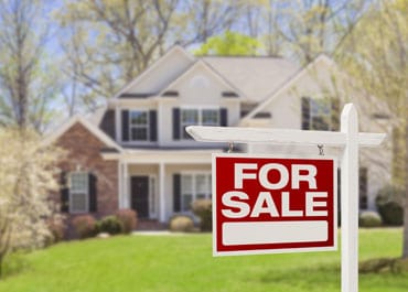 House with a prominent sign in front, indicating it is for sale - Legacy Law Centers